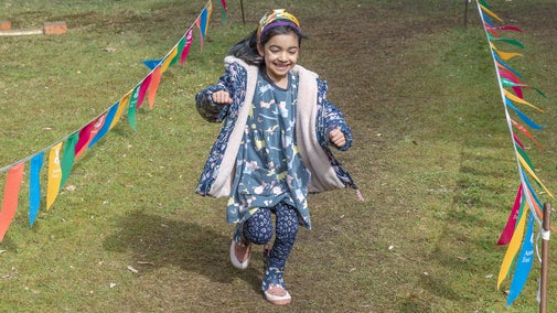 Girl with blue print dress and leggings enjoying the obstacle course in Ilex Grove at Cliveden, Buckinghamshire.